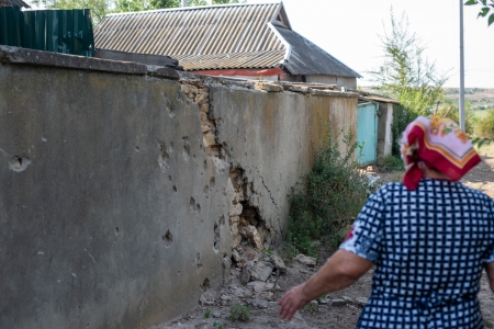 Lidia Fedorivna Aleksandrova (geb. 1937) vor einer Wand mit Einschusslöchern in einem Dorf im Gebiet Mykolajiw | Foto: Lesya Kharchenko